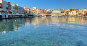 View across Chania Crete Greece harbor with crystal clear blue water and colorful old buildings in the background