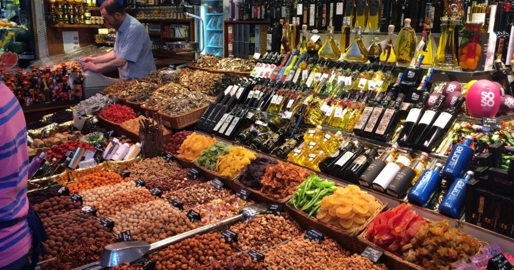 Barcelona market on las ramblas stand with olive oil bottles and bins of assorted fruits, nuts and other treats for sale