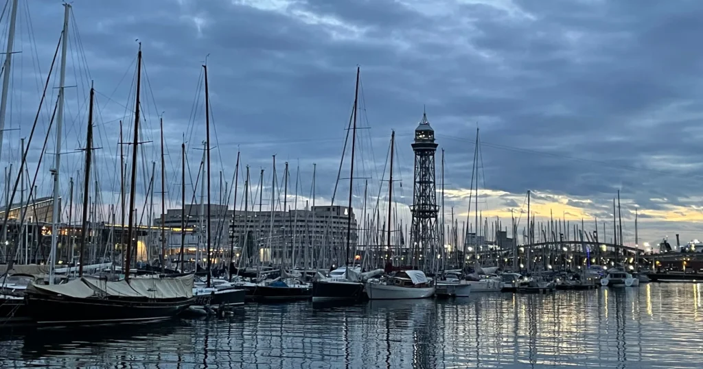 Barcelona waterfront at sunset with docks full of boats and light tower