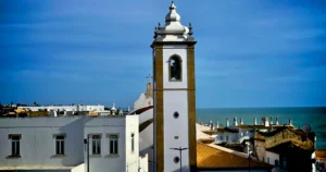 Albufeira Portugal street view with white clock tower in the center, clear blue sky in the background