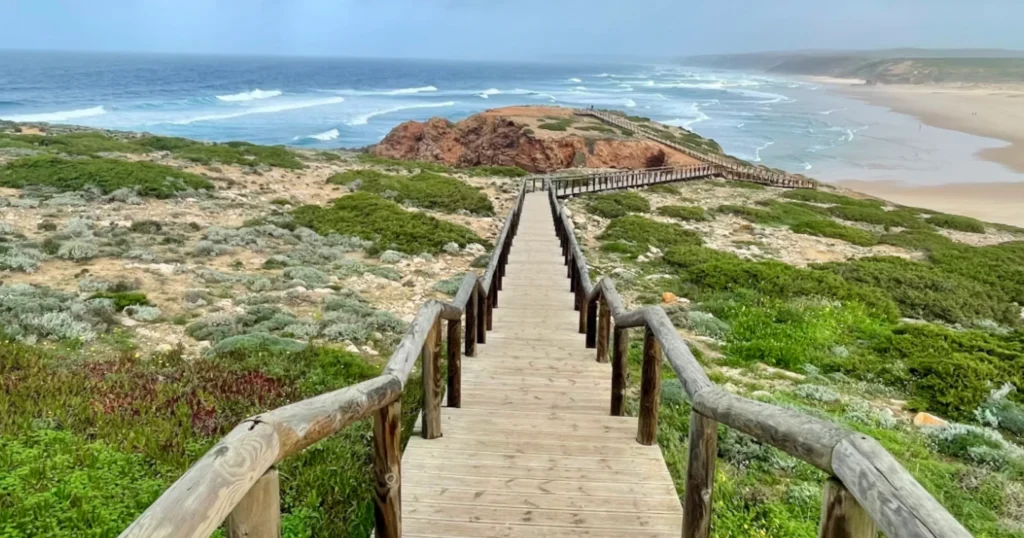 Vincentine Coast Natural Park image of long wooden walkway with log rails heading down to the beach with red cliffs in the background