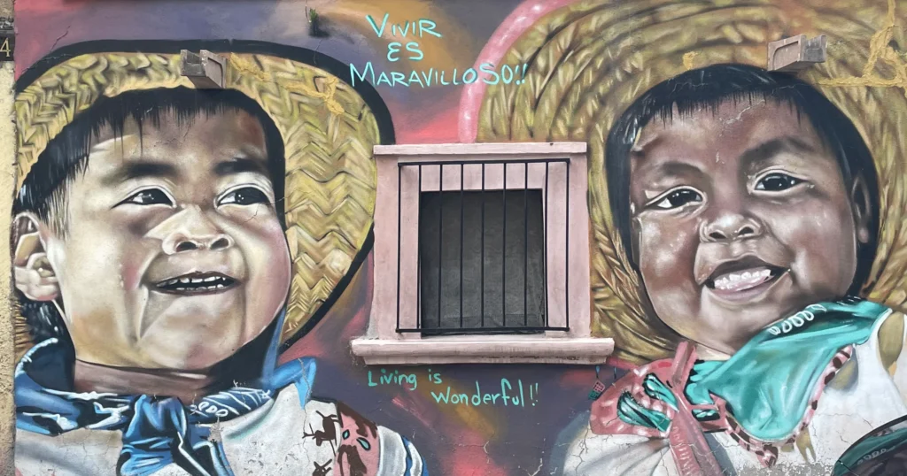 Barrio Guadalupe colorful street art image of tow children wearing straw hats painted on the side of a building