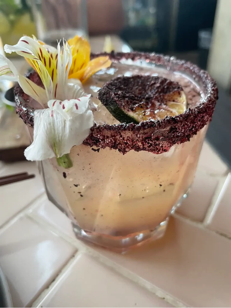 A drink at Inside Cafe with a decorative salt rim floating burnt orange and white and yellow flower decoration