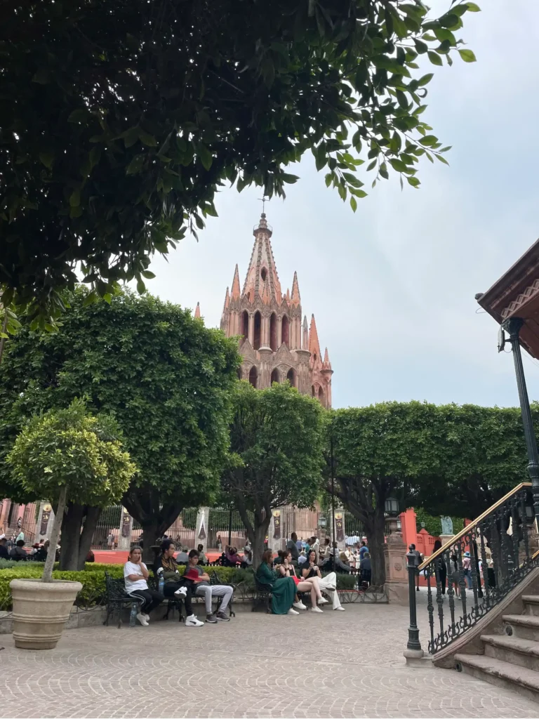 Jardin de Allende view with green manicured bushes and church rising up in the background