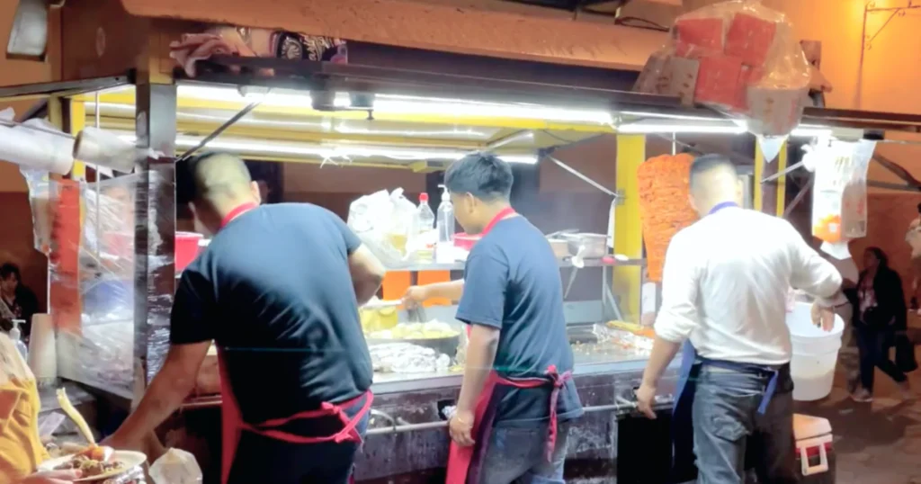 Image taken from behind of three men cooking at San Francisco taco cart at night in San Miguel de Allende Mexico