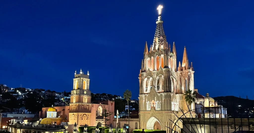 Parroquia de San Miguel Arcángel nightime view with church lit up against a dark blue night sky