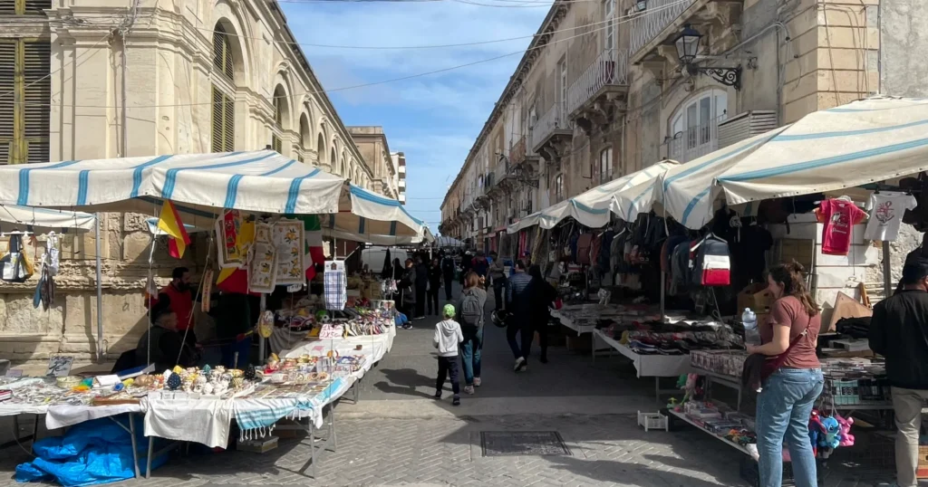 View down the street with stalls lining both sides of the Syracuse Market in Sicily