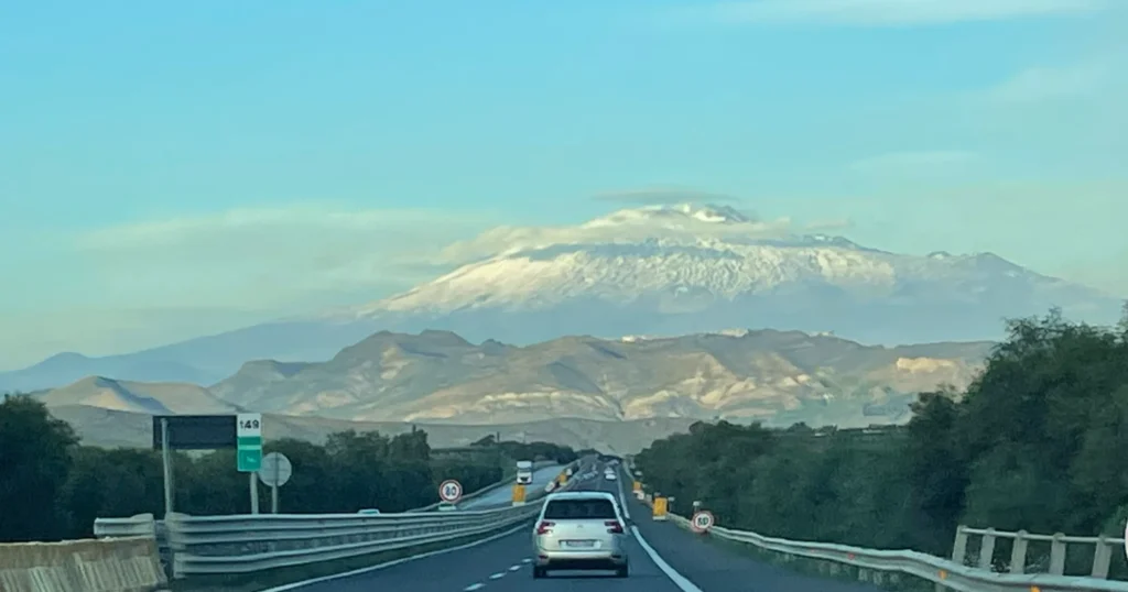 View driving down the highway with Mount Etna in the distance
