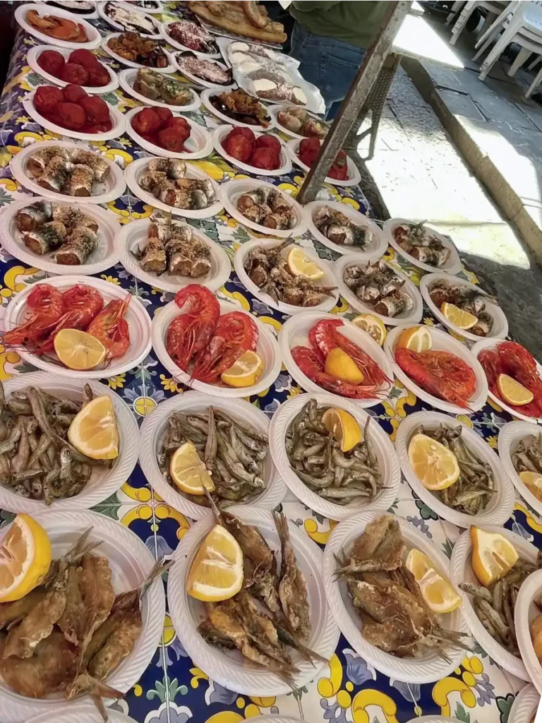 Small plastic plates filled with fresh seafood and lemon wedges at the Ballero Market in Sicily