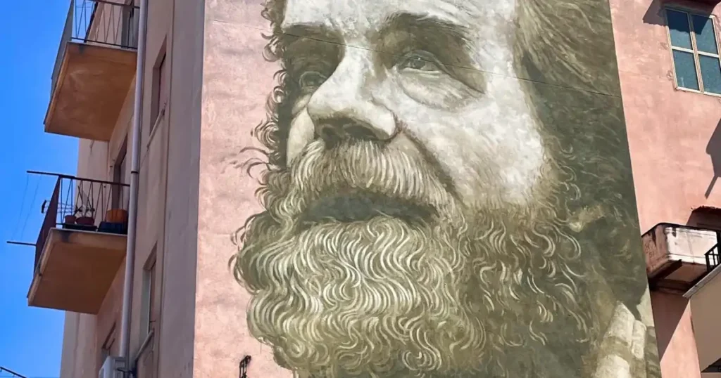 Mural of man with a beard on pink colored building in Palermo, Sicily