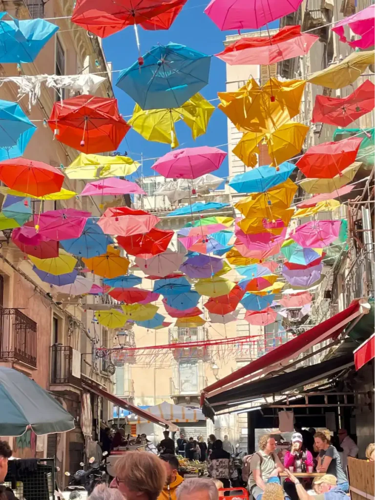 Multicolored umbrellas hanging across the street at the market in Sicily