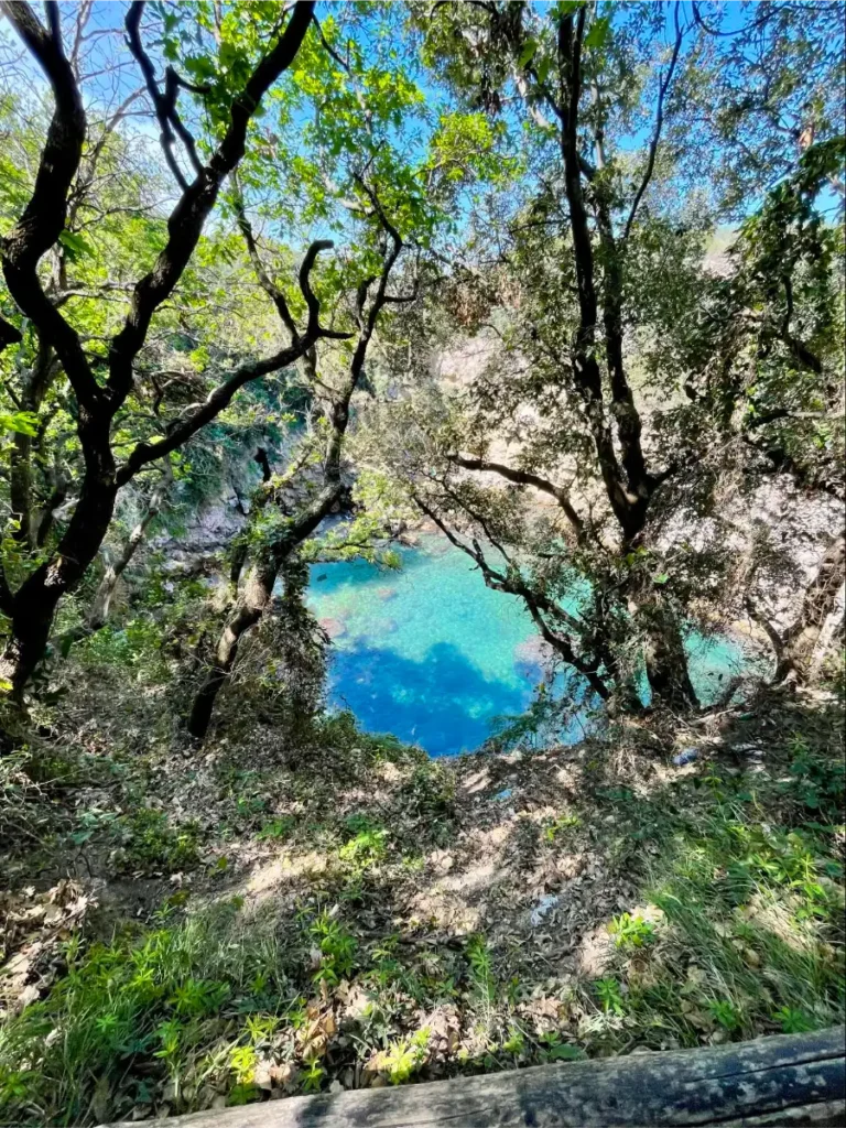 Looking through the trees into Baths of Regina Giovanna with clear blue waters