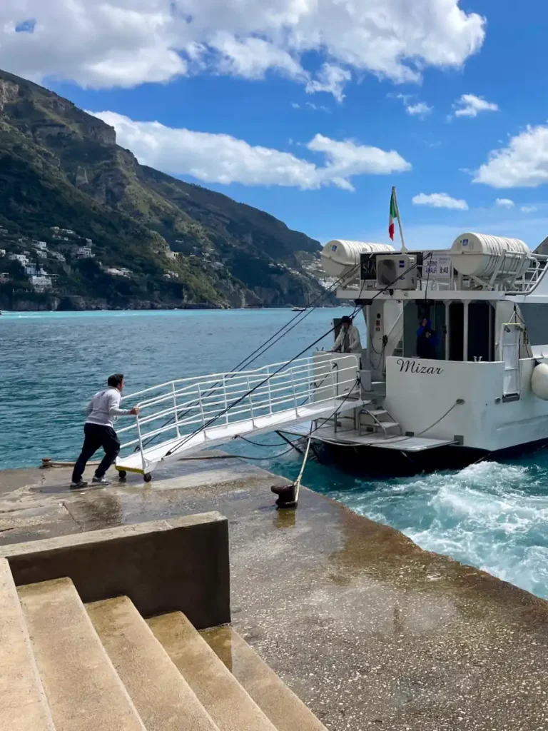 White ferry backed into a concrete pier with a boarding ramp off the back of the boat.