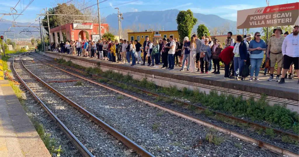 Train station in Pompeii with people on the platform waiting for the train.