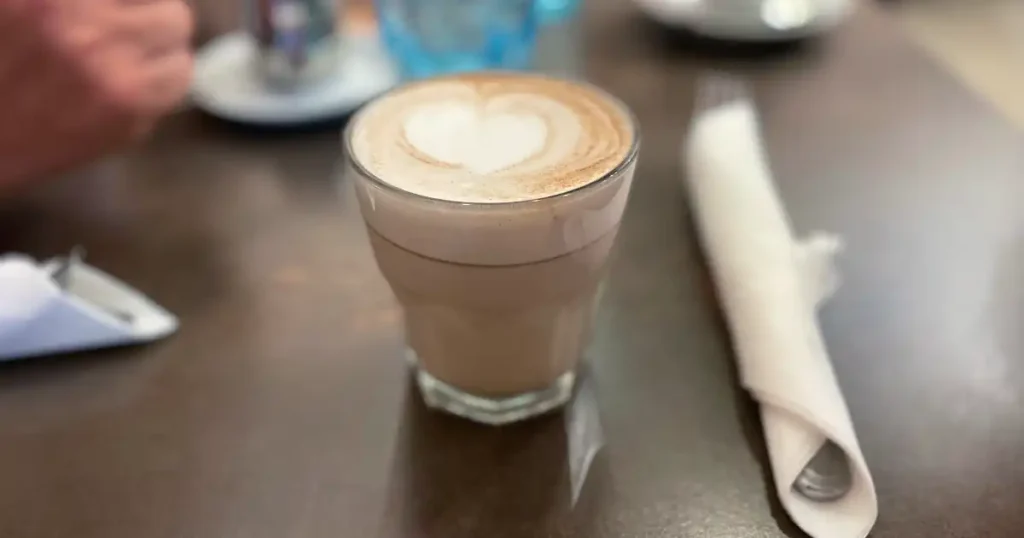 Cup of cappuccino in clear glass with heart design in the foam