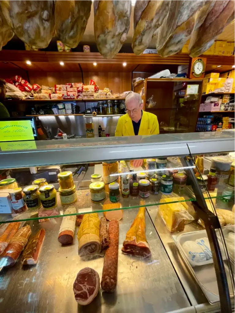 Sandwich counter with legs of prosciutto and a man behind the counter