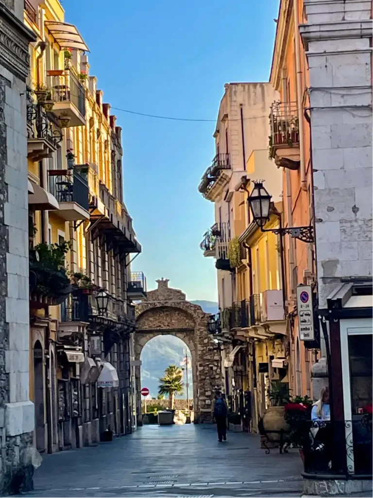 view of a Taormina street at sunset with the Messina Gate