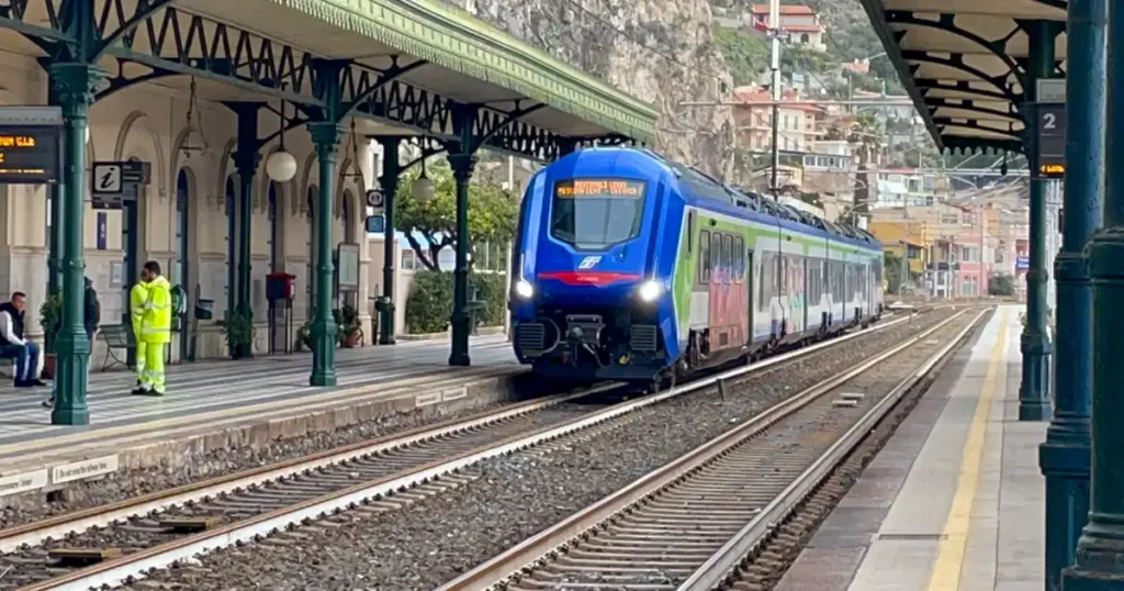 Taormina train station with blue and green train pulling in