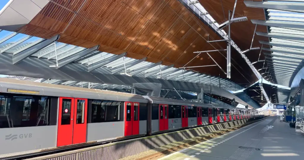 Red and grey train pulling into train station in Amsterdam