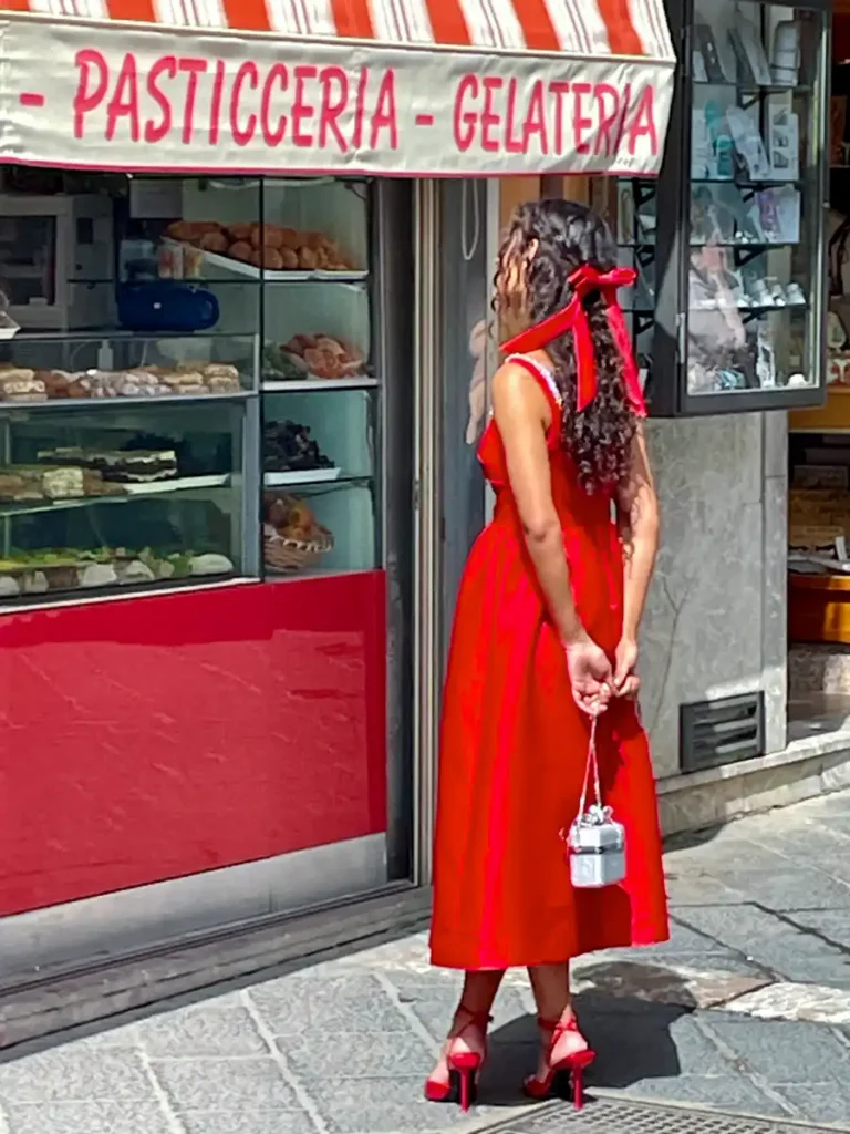 Woman in red dress standing in front of a red store front under a red and white striped awning