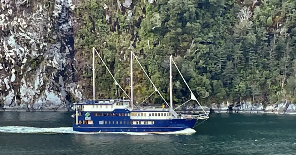 Blue boat cruising through Milford Sound