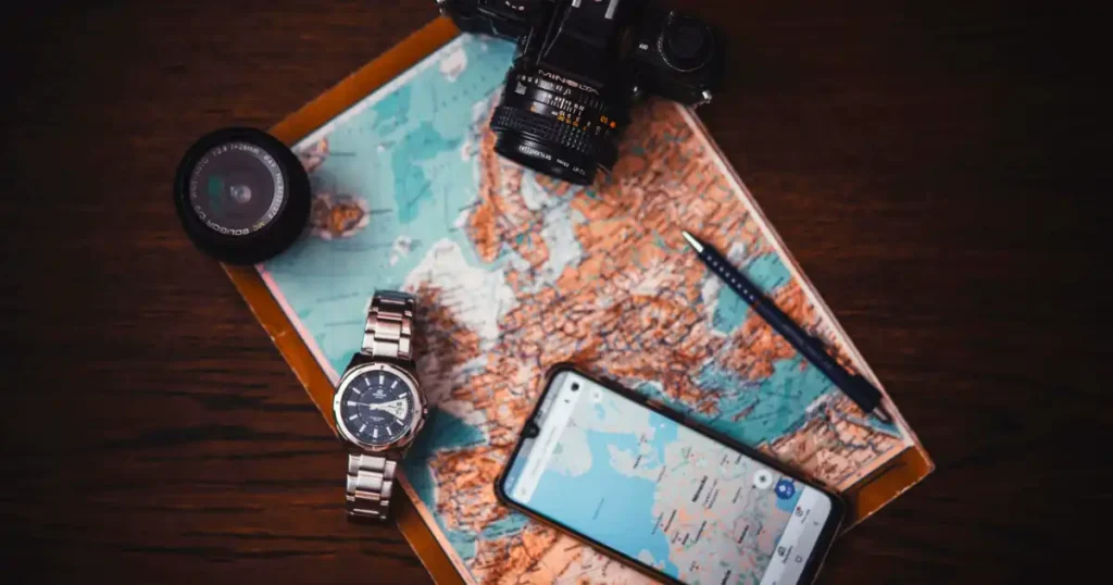 Watch Camera Smartphone and Map on wooden desk