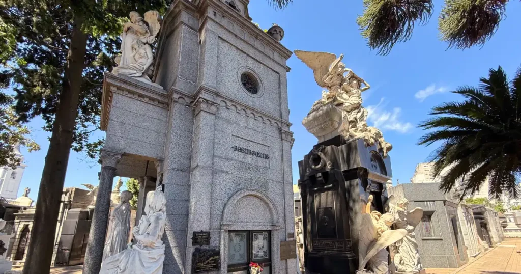 Recoleta cemetery with three graves and sign on a day with blue skies