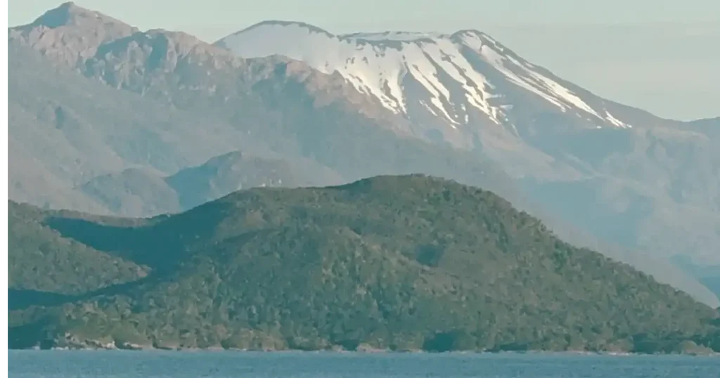 Sailing through Chilean Fjord with volcano in background topped with snow